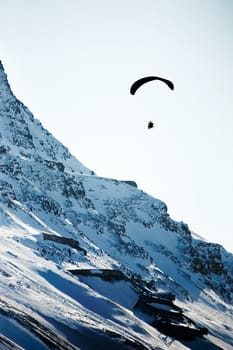 A paraglider travelling over a rocky mountain