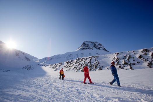Three people on a short mountain trek, against a beautiful winter landscape