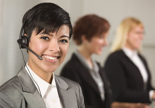 Pretty Hispanic Businesswoman with Colleagues Behind in an Office Setting.