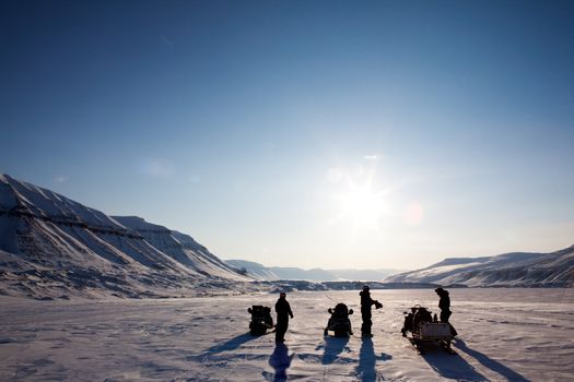 Three people on a winter snowmobile adventure in Svalbard, Norway