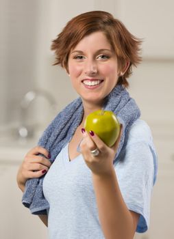 Pretty Red Haired Woman with Towel Holding Green Apple in Her Kitchen.