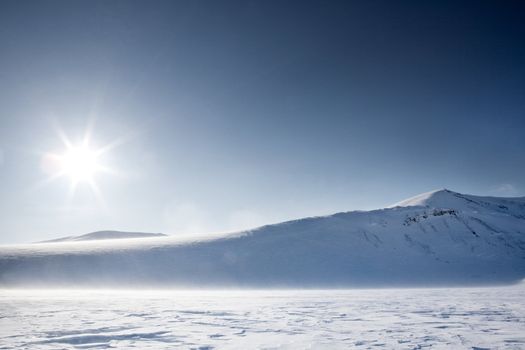 A wilderness winter mountain landscape looking into the sun