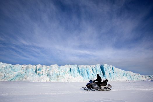 A glacier in Svalbard, Norway with a skidoo travelling on the ice