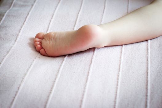 Children's foot close up on a light pink plaid