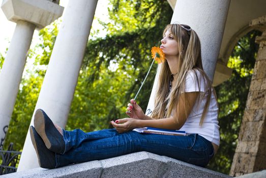 beautiful young woman with books and flower outdoor