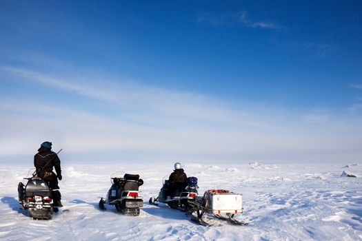 Three snowmobiles on a svalbard landscape of barren snow