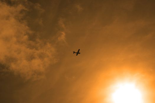 a silhouette of a light plane heading into the sunshine