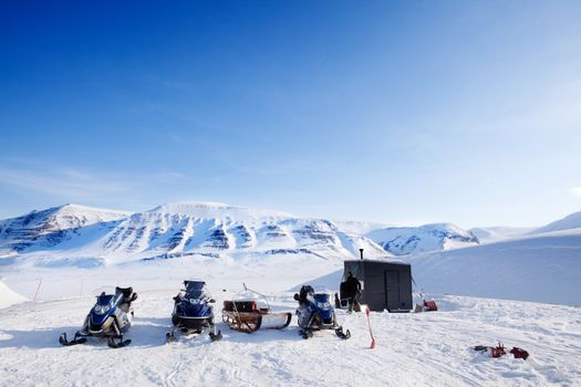 People preparing snowmobiles for an expedition through through winter conditions