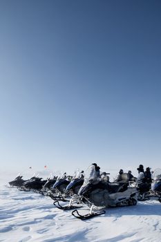 A large group of snowmobiles on a barren winter landscape