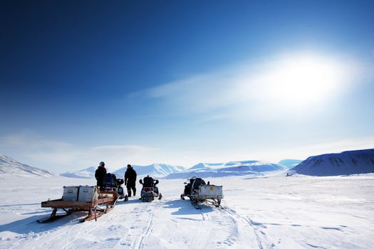 A group on a winter snowmobile adventure over a barren winter landscape