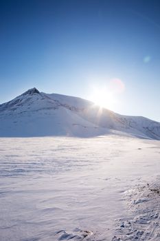 A winter landscape with a mountain and blue sky