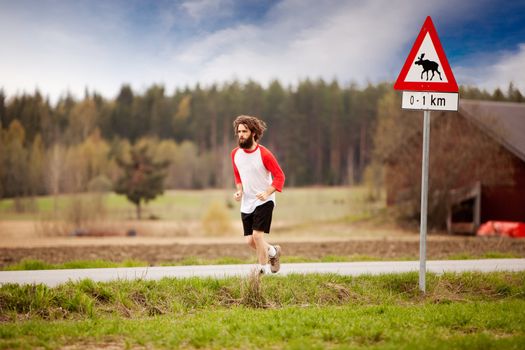 A runner with long hair and beard jogging in the country