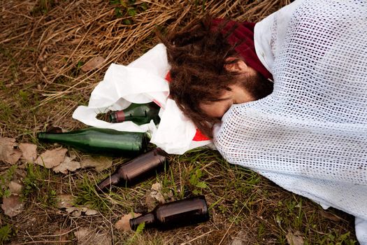 A person drunk sleeping in the ditch with liquor bottles