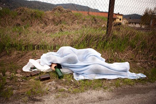 A homeless drunk person sleeping in the ditch