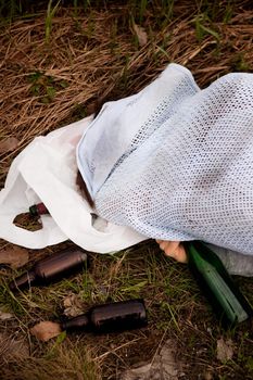 An alcoholic laying in the ditch with liquer bottles