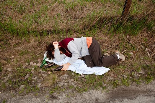 A drunk laying in the ditch with a number of bottles