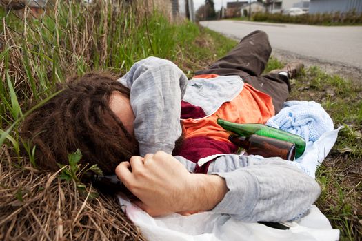 A homeless drunk person laying by the edge of the road