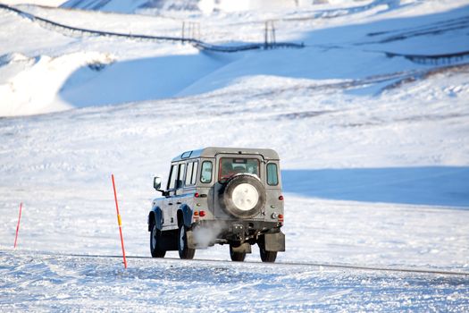 A truck driving on a barren landscape of snow and ice - Svalbard, Norway