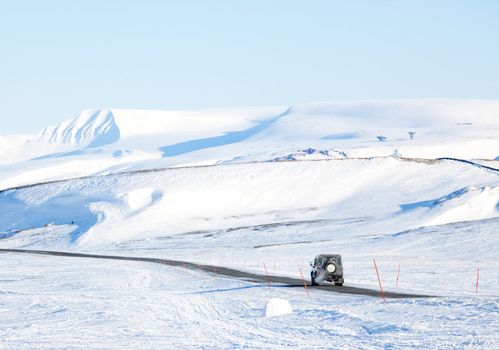 A truck driving on a barren landscape of snow and ice - Svalbard, Norway