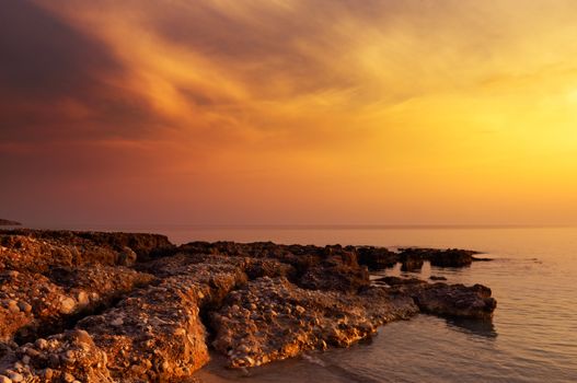 Image shows a rock formation under a spectacular sunset sky.