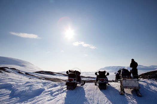 Three snowmobiles on a Svalbard Landscape - winter adventure