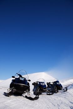 Three snowmobiles on an outdoor winter landscape