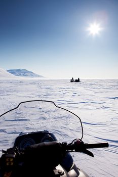 Three snowmobiles on an outdoor winter landscape