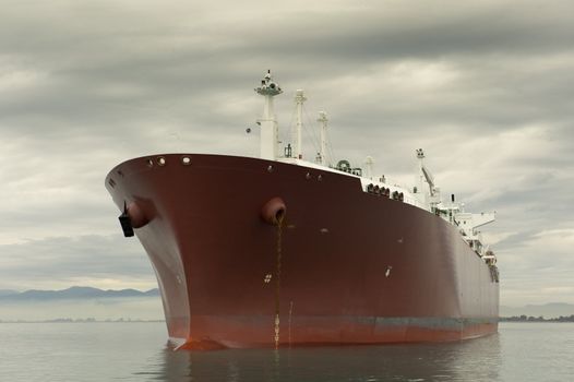 Large red liquefied gas carrier ship anchored near the shore