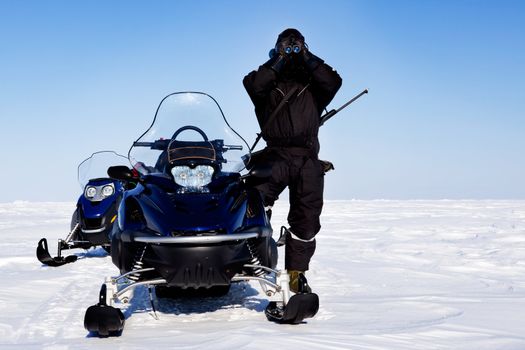 An expedition guide and a couple of snowmobiles on a winter landscape