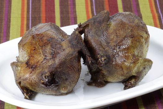 Two crunchy fried pigeons on a plate