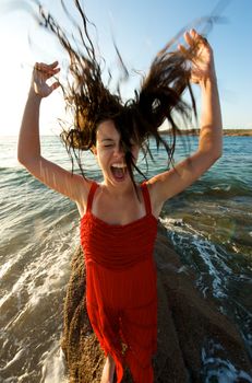 Pretty girl moving her hair on the beach at sunset time