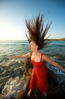 Pretty girl moving her hair on the beach at sunset time