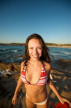 Wonderful pretty girl wearing a bikini posing on the beach at sunset tim