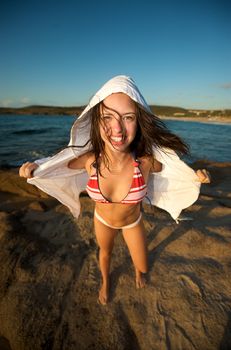Wonderful pretty girl wearing a bikini posing on the beach at sunset tim