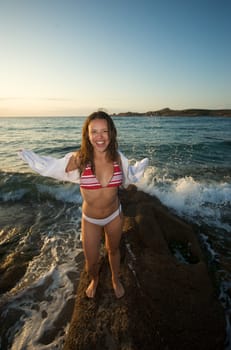 Wonderful pretty girl wearing a bikini posing on the beach at sunset tim