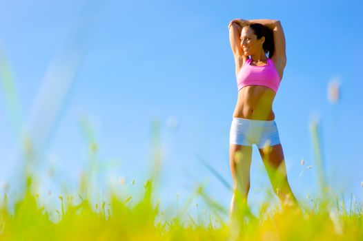 Athletic woman working out in a meadow, from a complete series of photos.