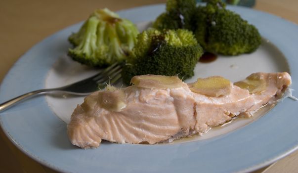 Plate with fish topped with ginger with broccolis on the side