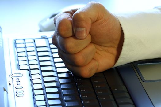 Businessman's fist on laptop, showing anger, excitement