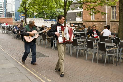 two Gipsy street performers playing guitar and accordion on canal street , Manchester, UK