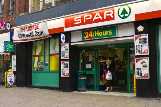 woman exiting Spar Shop with a plastic,carrier bag