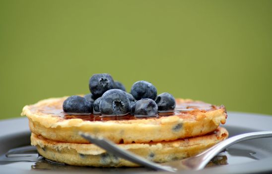 blueberry waffles on a plate with fork and fresh blueberries