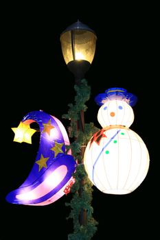 wizard hat and snowman lanterns hanging at a lamp post
