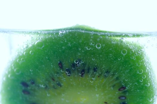 close-up slice of kiwi in water with bubbles