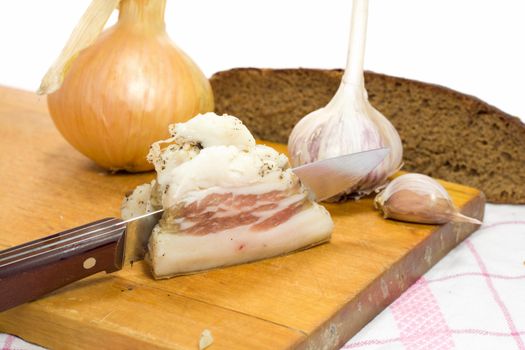 lard, garlic, onion, bread, board on table-cloth, isolated