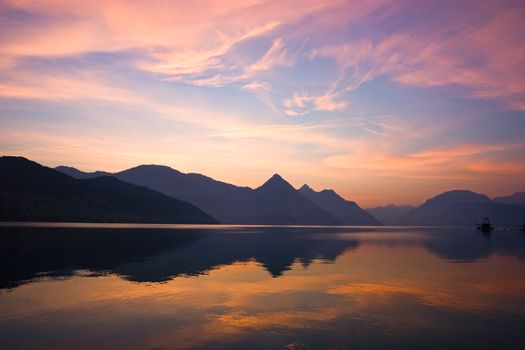 Beautiful sunrise over mountains, reflected on lake. Central Switzerland.