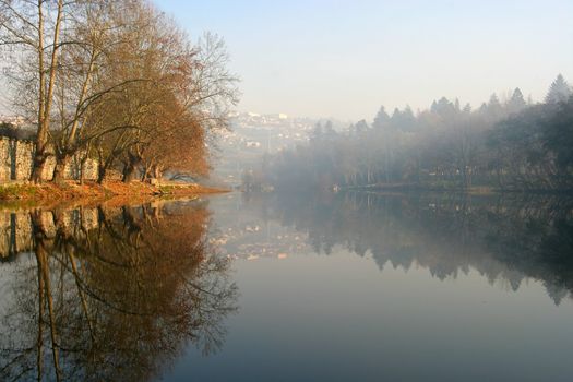 Beautiful fall landscape. Fall colored trees reflected on still river. Portugal.