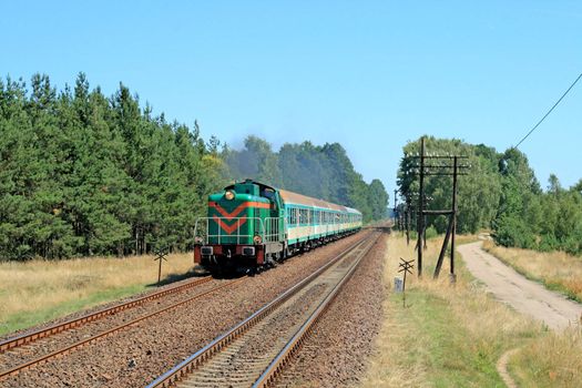 Rural summer landscape with train hauled by the diesel locomotive
