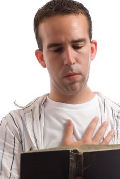 A religious man is reading an old bible while holding one hand over his heart, isolated against a white background