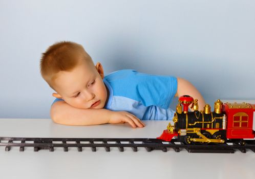 Little boy playing with a toy locomotive at home