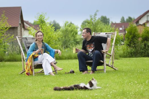 Portrait of happy couple drinking tea on deck chairs